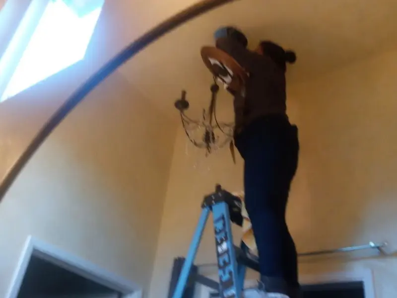 Electrician installing a chandelier in a Granbury residence